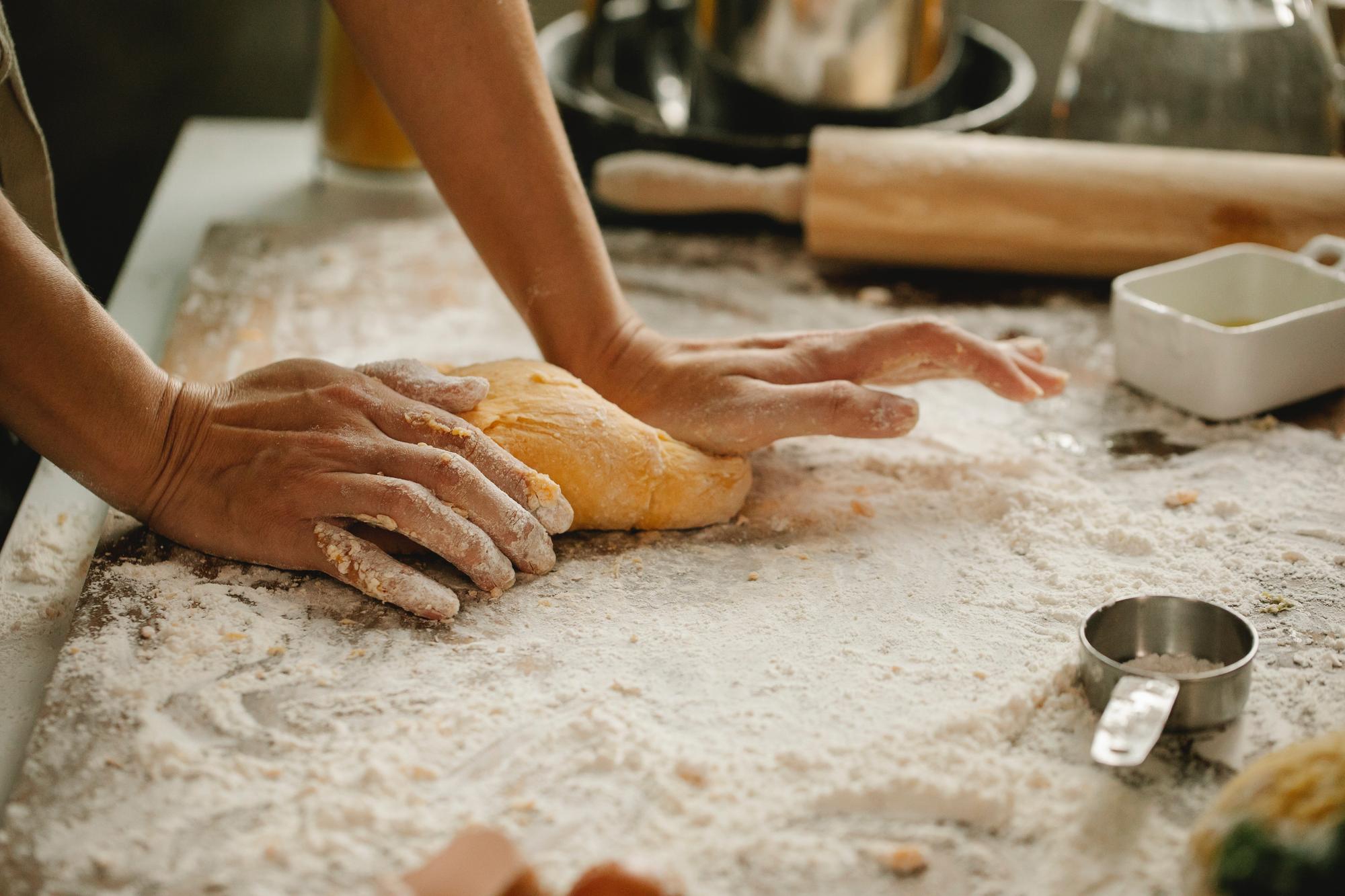 close-up of hands kneading dough in warm kitchen
